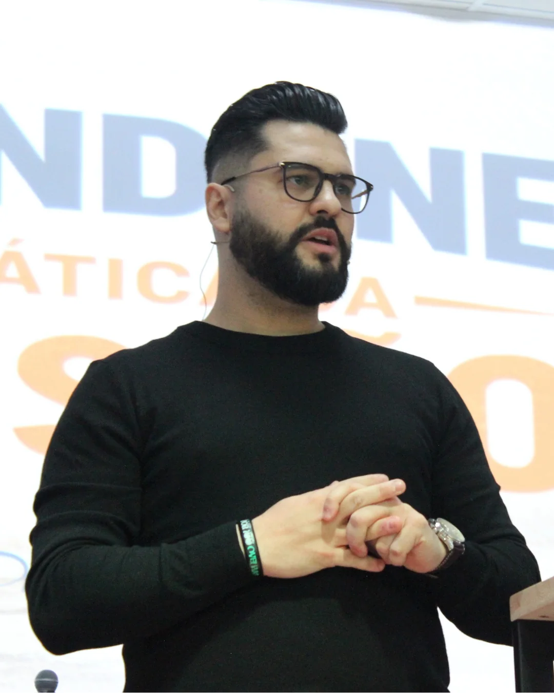 Il Pastore Thomas Abelini con un maglione nero e le mani giunte, durante un evento